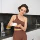 Mujer sirviendo cápsulas de un frasco en la mano, en una cocina